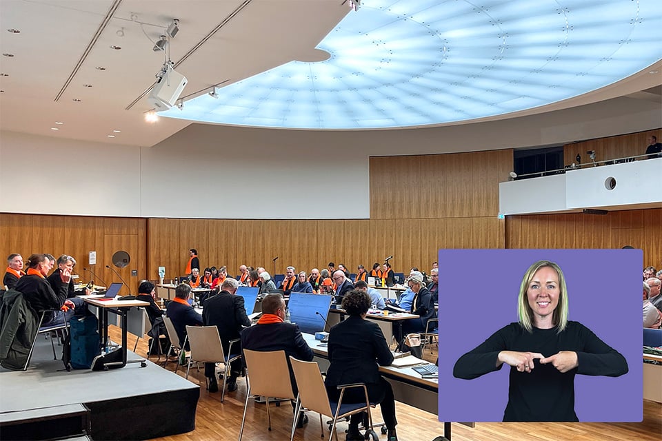 Image of a government meeting with an AI sign language avatar overlayed